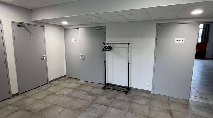 Pièce vide avec porte, interrupteur, prise, et sol carrelé.