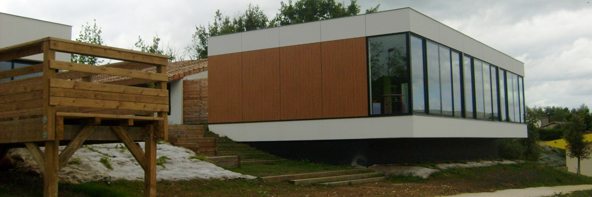 Maison moderne avec bois, verre, escalier en bois, terrain incliné, végétation.