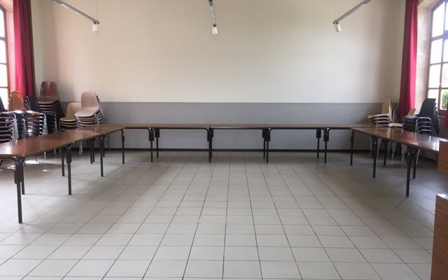 Salle avec tables, chaises, lumières et fenêtres.