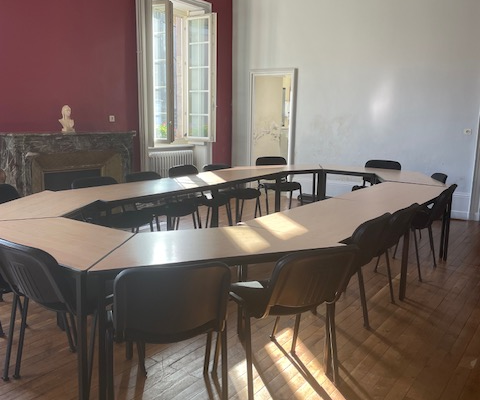 "Salle avec tables, chaises, cheminée, luminaires et fenêtres."