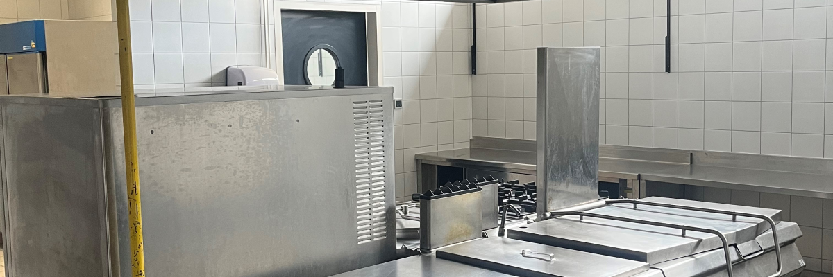Cuisine professionnelle avec plans de travail, fours, plaques de cuisson, hottes et équipements de cuisine en acier inoxydable.
