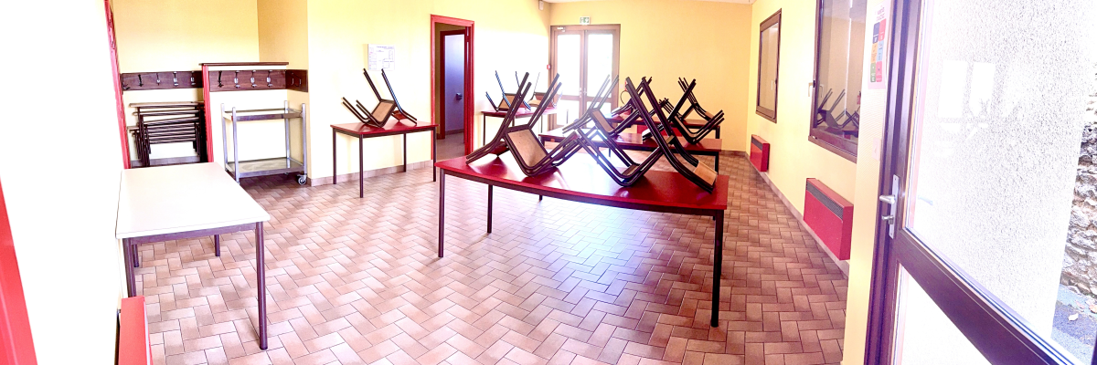 Salle avec tables, chaises empilées et armoires métalliques.
