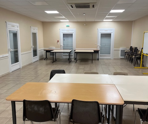 Salle avec tables, chaises, portes et climatisation.