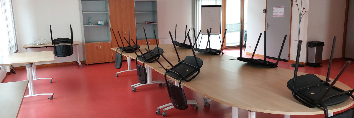 Salle avec tables rondes, chaises, vitrine, porte-manteau et portes.