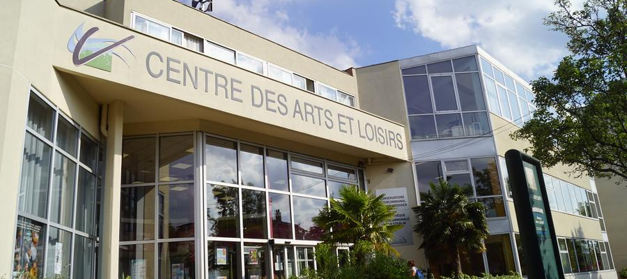 Bâtiment avec enseigne "Centre des Arts et Loisirs," grandes vitres, plantes, ciel.