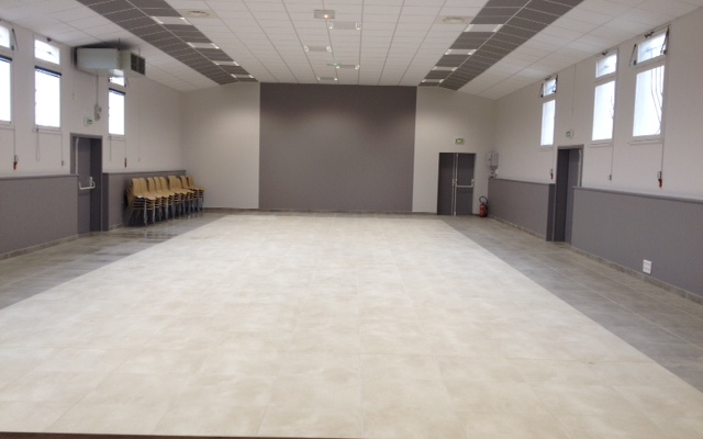 Salle vide avec rangée de chaises, projecteur, portes et fenêtres.