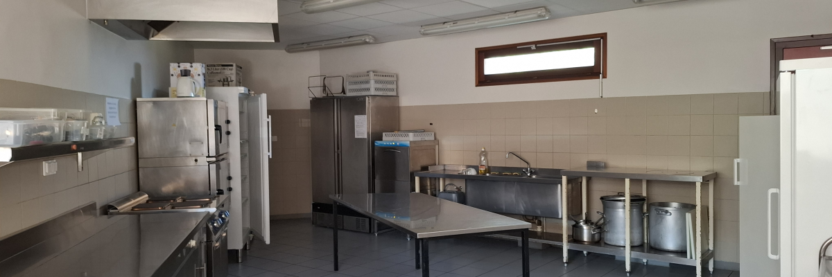 Cuisine équipée avec plans de travail, fours, réfrigérateurs, éviers, tables et chariots.