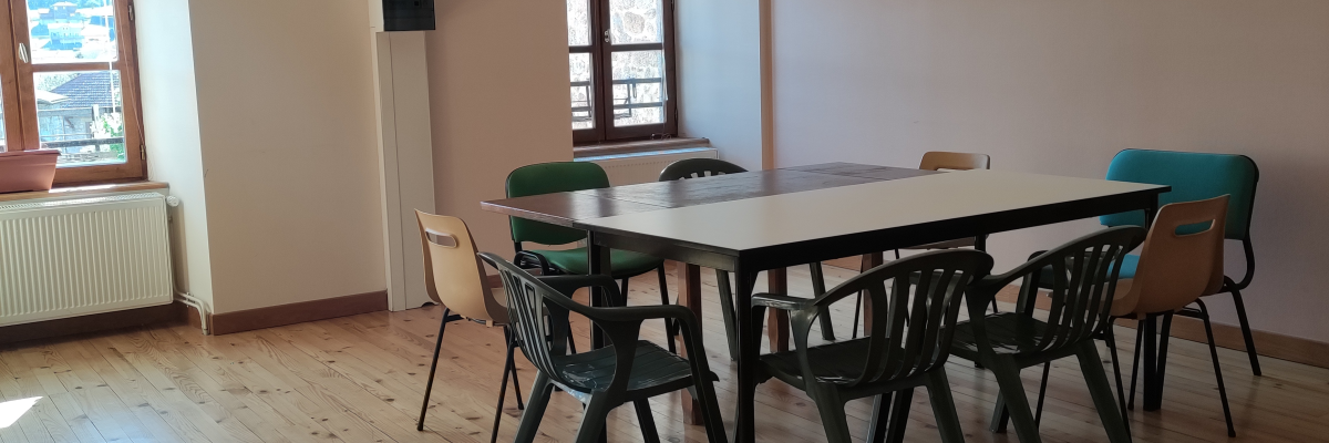 Salle avec table, chaises, haut-parleurs et fenêtres.