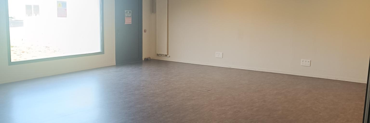 Salle vide avec sol, murs, fenêtres, portes et éclairage au plafond. Une chaise visible.