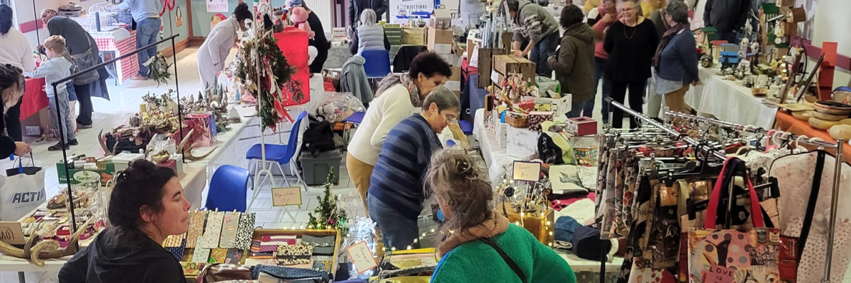 Salle avec tables, étalages, personnes, et divers articles exposés.