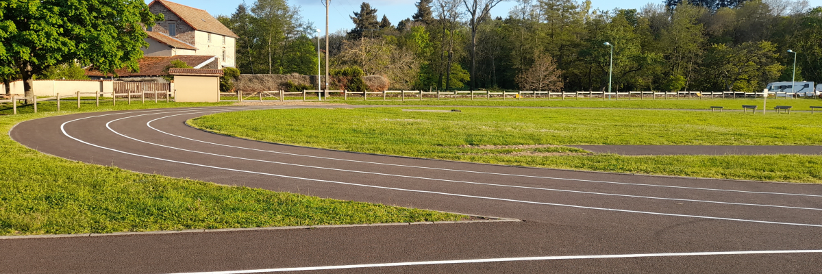 Parking avec lignes de marquage, pelouse, arbres, bâtiment et poteaux électriques.