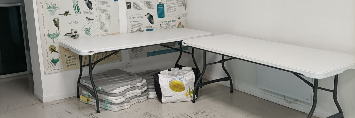 Table avec piles de papier et affiches au mur.