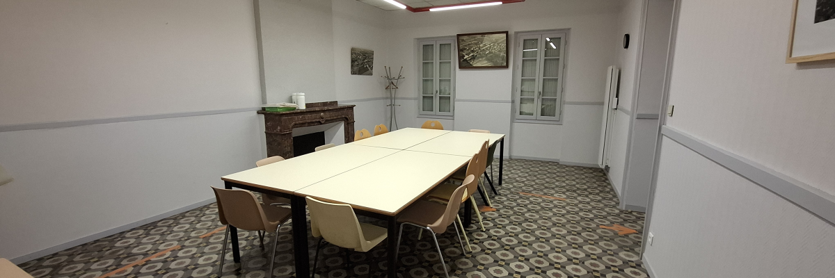 Salle avec table, chaises, cheminée, tableaux et porte.
