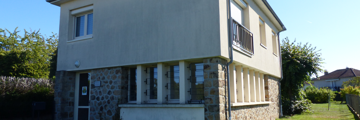 Maison à deux étages avec porte d'entrée, fenêtres, balcon et pelouse.