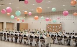Salle de réunion avec tables, chaises, ballons suspendus et décor mural.