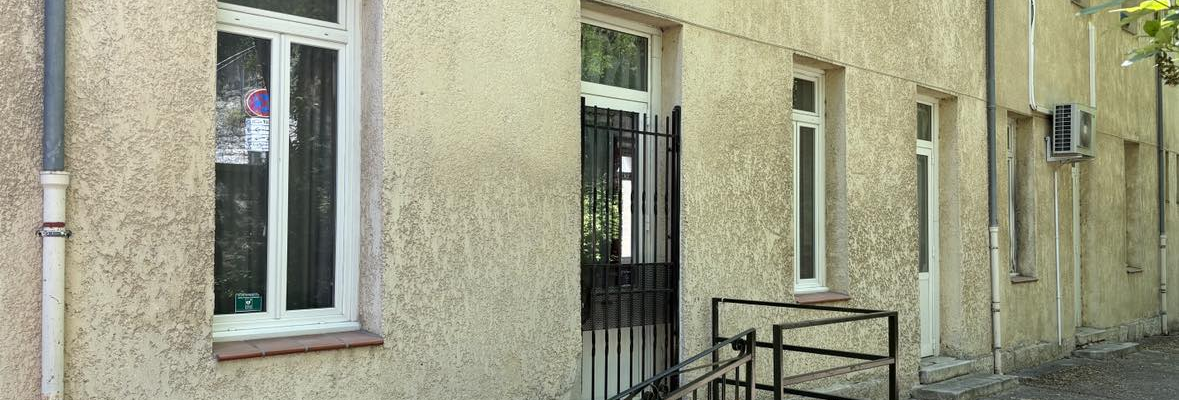 Bâtiment avec enseigne "Maison Pour Tous", porte avec rampe, fenêtres et climatiseurs.