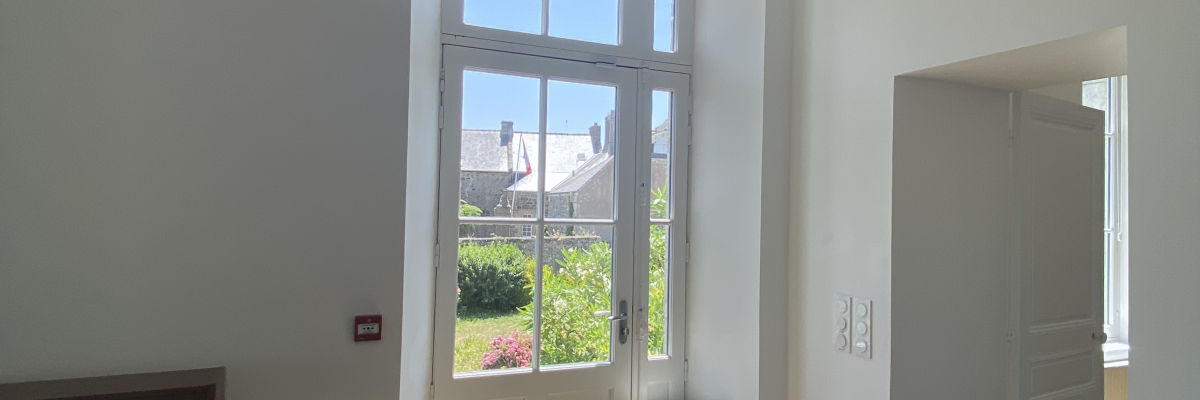 Pièce avec chaises, table, fenêtre, extincteur, prise électrique.