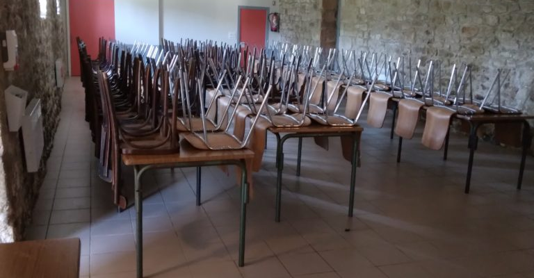 Salle avec tables, chaises, verre à pied et murs en pierre.