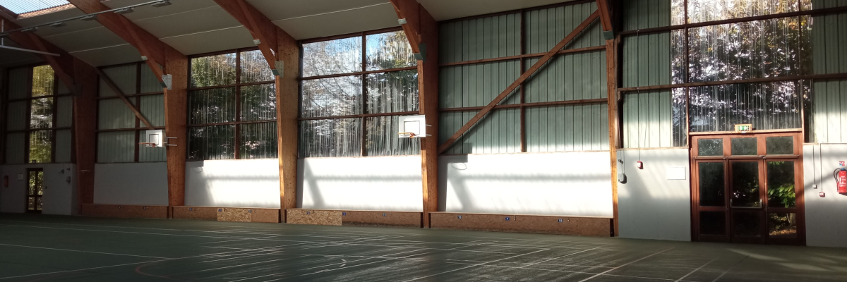 Salle spacieuse avec sol en parquet, vitres, portes en bois et toit en verre.