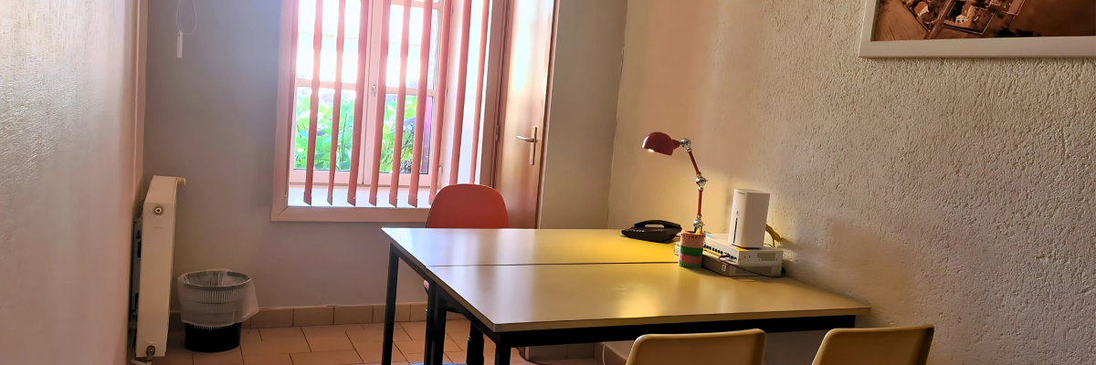 Pièce avec table, chaises, lampe, radiateur, téléphone, corbeille à papier et cadre photo.