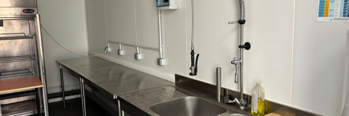 Cuisine avec plans de travail, évier, robinets, lave-mains, four et distributeur de savon.