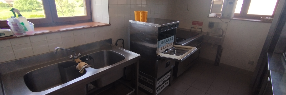 Cuisine équipée avec évier, four, hotte, plan de travail et fenêtres.