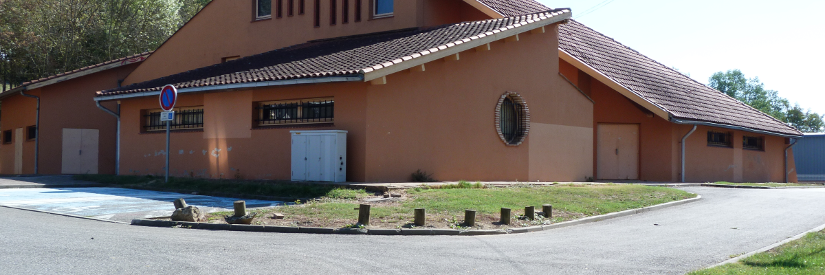 Bâtiment avec toit en tuiles, portes sectionnelles et panneau d'arrêt.