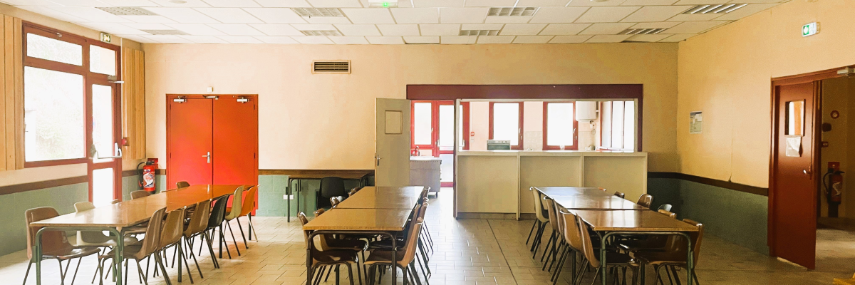 Salle avec tables, chaises, placard, réfrigérateur et portes.