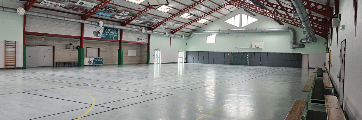 Gymnase avec panier de basket, mur d'escalade et bancs.