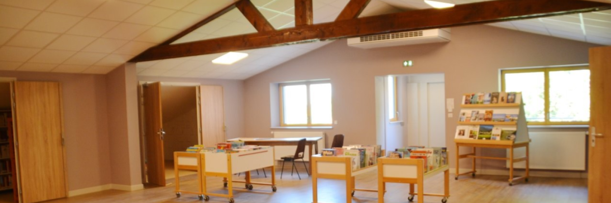 Salle avec tables, chaises, étagères, livres, portes et fenêtres.