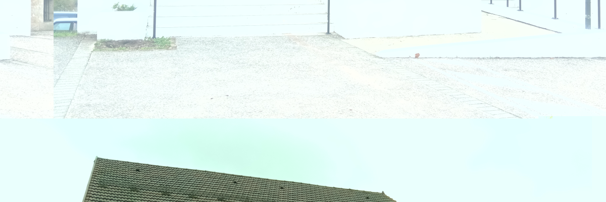 Bâtiment avec entrée, parking et lampadaire.