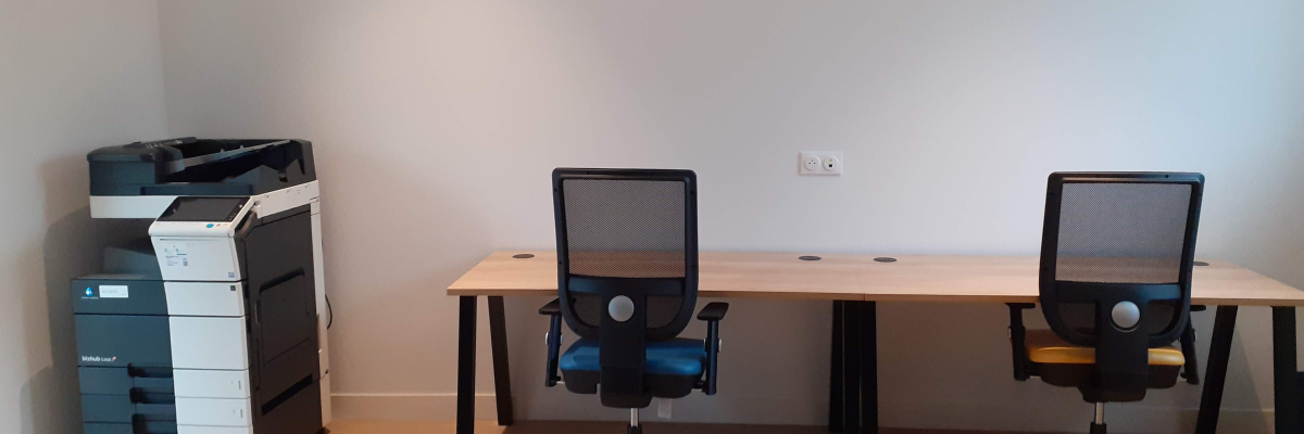 Bureau avec imprimante, deux chaises et table.