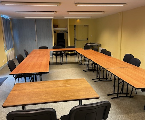 Salle de classe avec tables, chaises et tableau.