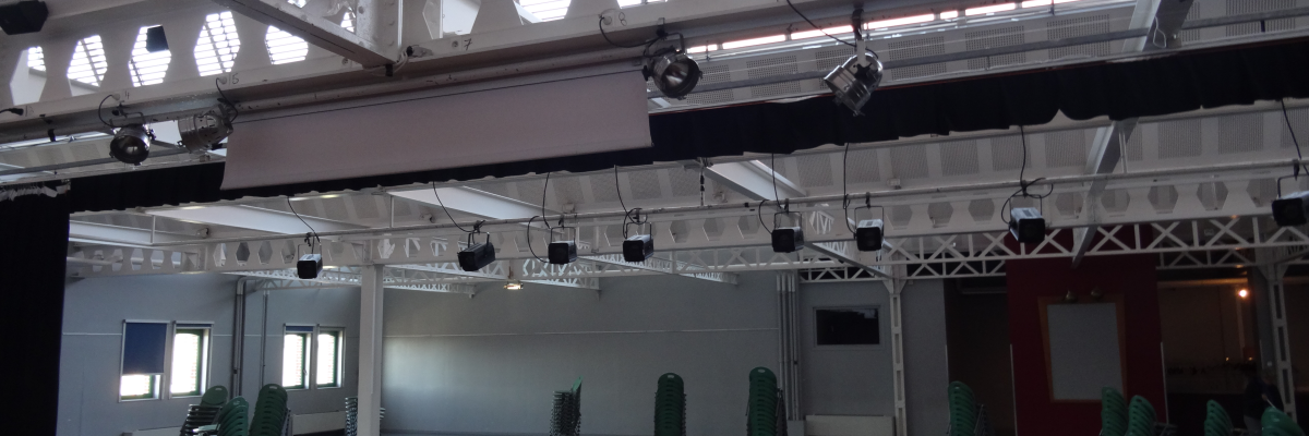 Salle avec chaises, spots, miroirs, structure métallique, fenêtres et rideaux.