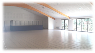 Salle vide avec sol carrelé, murs blancs, fenêtres, escalier et rampes bleues.