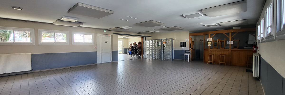Salle spacieuse avec bar, tabourets, distributeur automatique et portes.