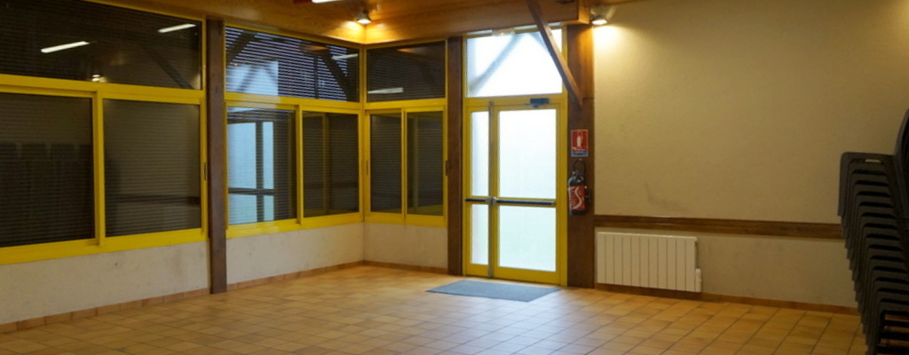 Salle avec portes vitrées, radiateur, tapis et chaises empilées.
