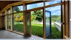 Pièce avec grandes fenêtres, vue sur pelouse et montagne.