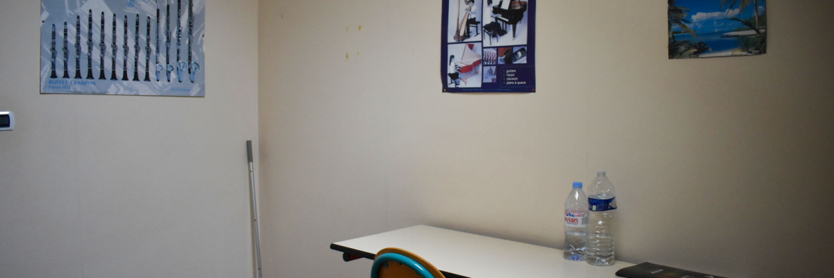 Pièce avec table, chaise, bouteille d'eau et trois affiches sur le mur.