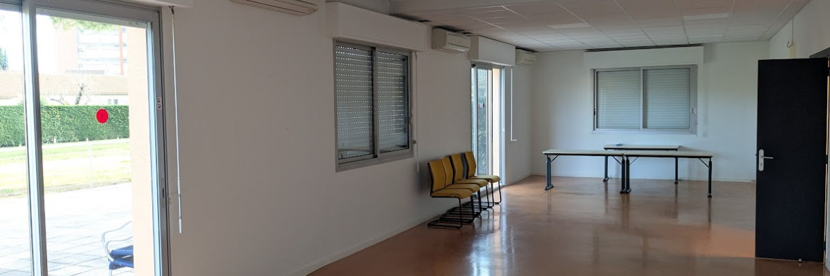 Pièce avec tables, chaises, climatiseurs, fenêtres et porte.