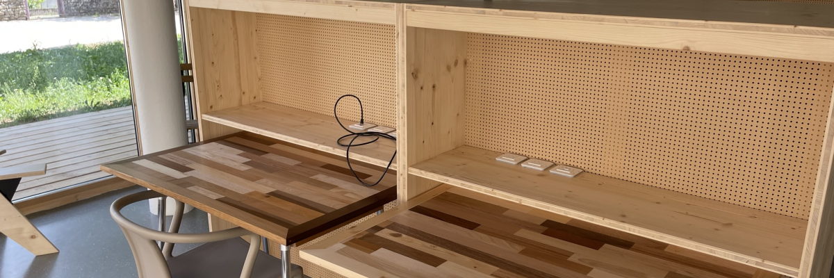 Bureaux en bois, chaises, étagères ouvertes, murs en verre, radiateur.