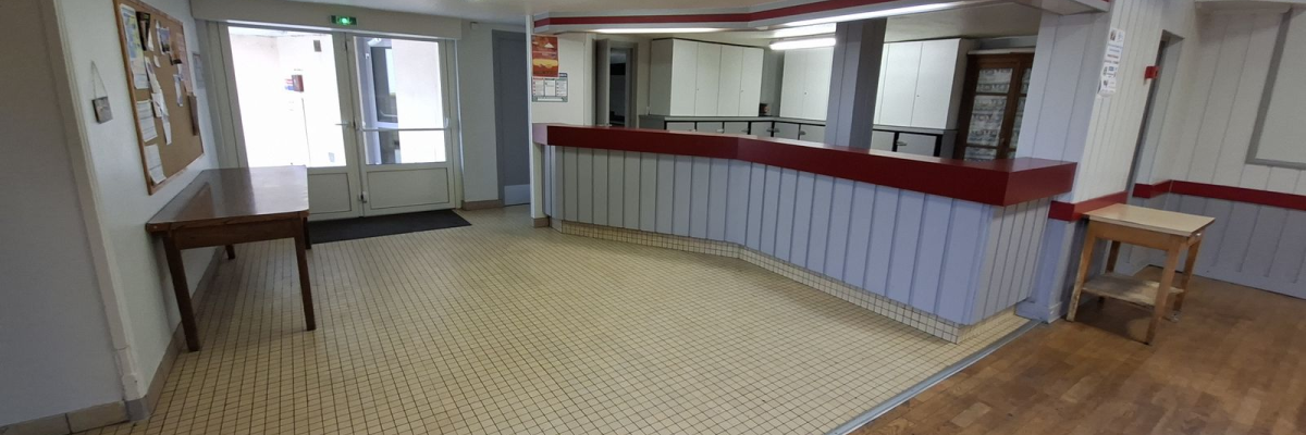 Grande pièce avec sol en carreaux, comptoir avec tabourets, tables, portes et climatiseur mural.