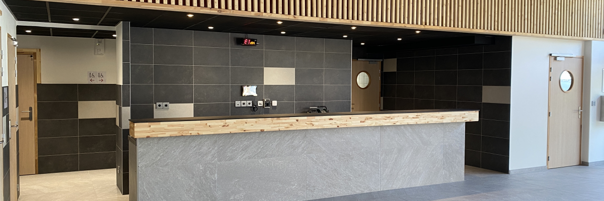 Réception avec comptoir, écrans, horloge et portes.