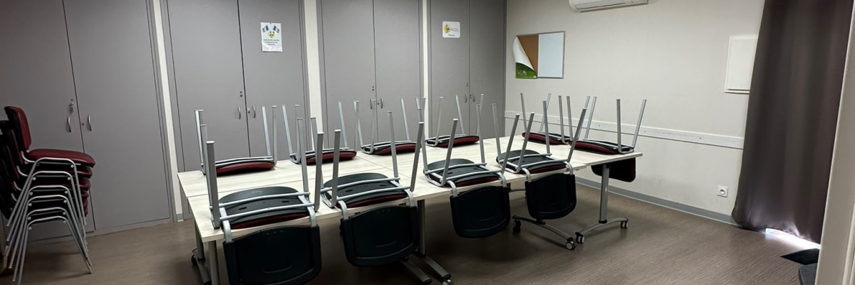 Salle avec tables, chaises, chariots et éclairage au plafond.