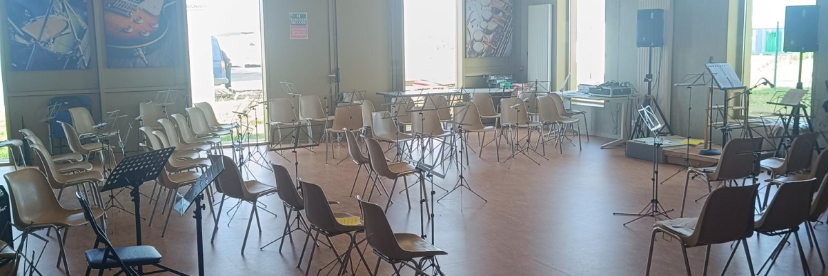 Salle avec chaises, pupitres, fenêtres, œuvres d'art murales et éclairage moderne.