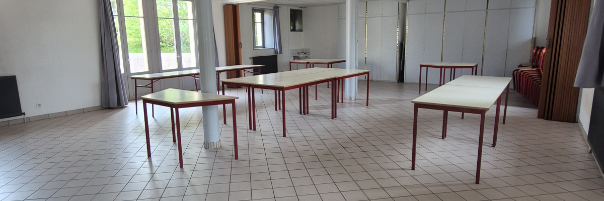 Salle avec tables, chaises, et colonnes.