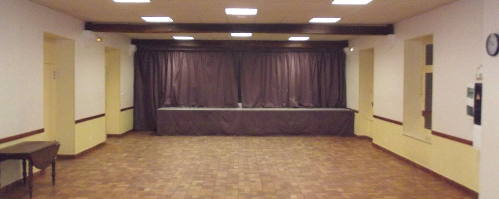 Salle avec scène, rideau, tableau de bord et porte.