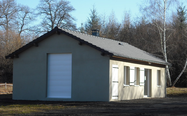 Bâtiment avec porte de garage, fenêtres et porte d'entrée.