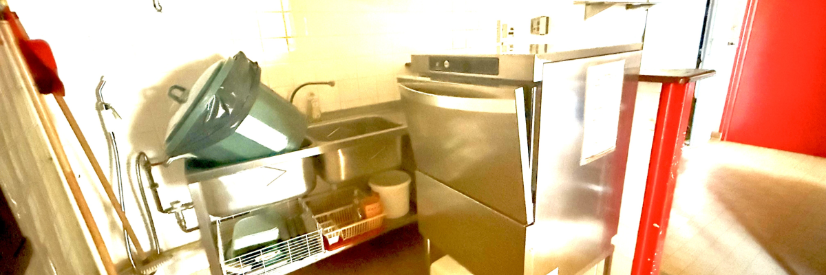 Salle avec évier, laveuse, sécheuse, étagères et produits ménagers.