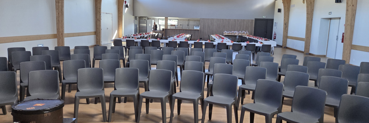 Salle avec rangées de chaises, tables, extincteur, et trépied.